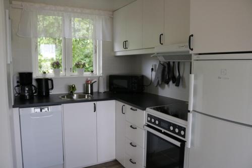 a kitchen with white cabinets and a white refrigerator at Kärraton Stugor in Åhus