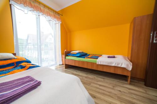 a yellow room with two beds and a window at Noclegi u Bernadków in Jurgów
