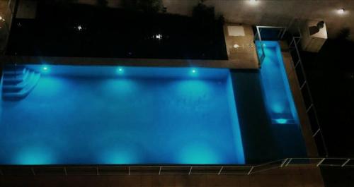 una gran piscina de agua azul por la noche en M & C Suites en Buenos Aires