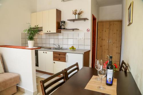 a kitchen and a table with a bottle of wine at Matea Apartments Milna in Milna