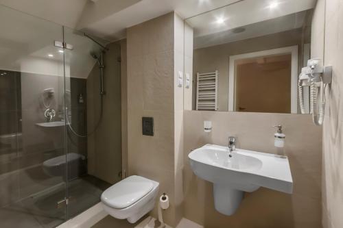 a bathroom with a sink and a toilet and a shower at Hotel Rozbicki in Włocławek
