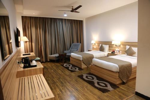 a hotel room with two beds and a chair at Ana Clarks Inn, Panchkula in Panchkula