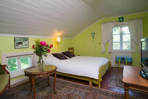 Un dormitorio con una cama y un jarrón de flores sobre una mesa. en Koivulan Kartano, en Lohja
