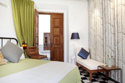 a bedroom with a bed and a chair and a window at Del Carmen Concept Hotel Boutique by Chai in Guadalajara