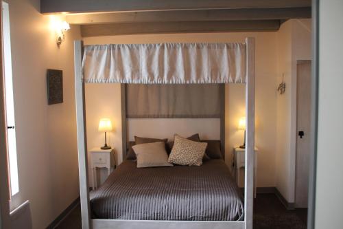 a bedroom with a canopy bed with two lamps at Les Terrasses des Mimosas in Caumont-sur-Garonne