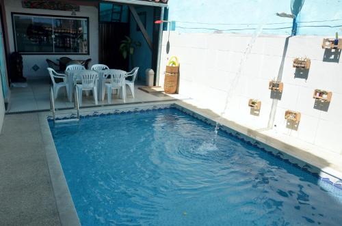 una piscina con sillas blancas y una fuente en Pousada Mandala en Búzios