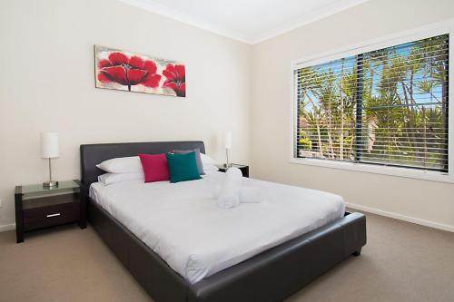 a bedroom with a large bed with a window at Pandanus - Lennox Head in Lennox Head