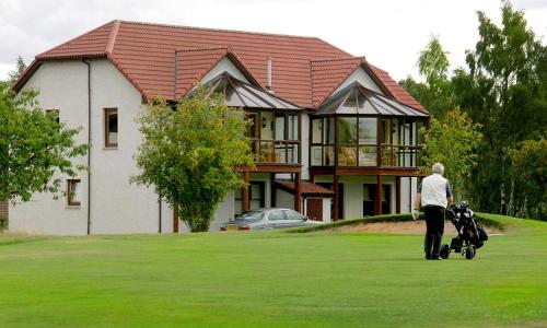 a man walking with a stroller in front of a house at Macdonald Spey Valley Resort in Aviemore