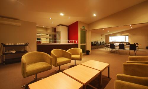 a waiting room with chairs and tables and a kitchen at Park View Motor Lodge in Hamilton