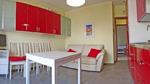 eine Küche und ein Wohnzimmer mit einem weißen Tisch und roten Schränken in der Unterkunft La Quiete 23 Lake view apartment by Gardadomusmea in Tremosine sul Garda