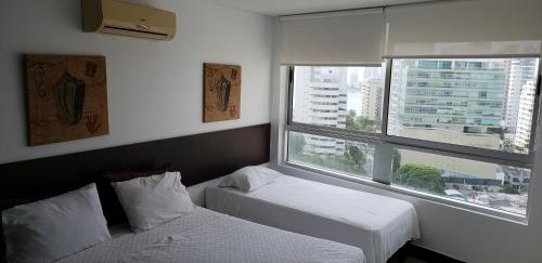 a hotel room with two beds and a window at Palmetto Eliptic Bahia in Cartagena de Indias