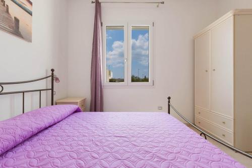 1 dormitorio con cama morada y ventana en Residence Pianeta Mare, en Torre Lapillo