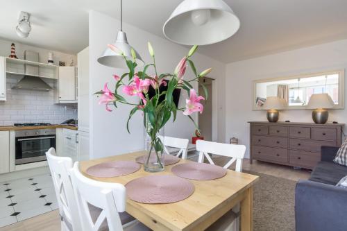 a kitchen and dining room with a table with pink flowers at Elite Apartments Center Grobla in Gdańsk