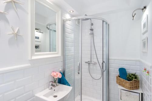 a white bathroom with a shower and a sink at Elite Apartments Center Grobla in Gdańsk