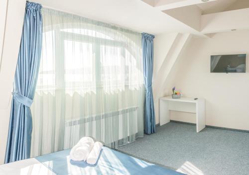 a bedroom with a large window with blue curtains at Family Hotel Belle Epoque Beach in Varna City