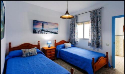 1 dormitorio con 2 camas y ventana en Apartamento de las Flores en Conil, en Conil de la Frontera