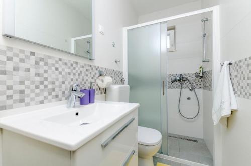 a white bathroom with a sink and a shower at Apartments Danica in Primošten