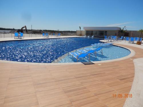 une grande piscine avec des chaises bleues. dans l'établissement Flat entre Mar e Lagoa, à Arraial do Cabo