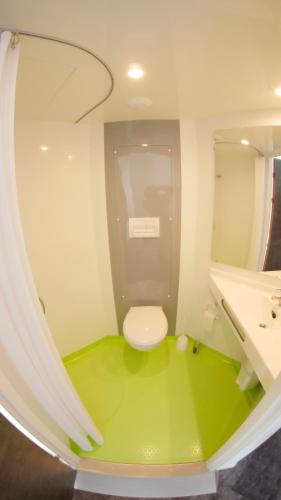 La salle de bains est pourvue de toilettes et d'un sol vert. dans l'établissement Hôtel du Tramway, à Laon