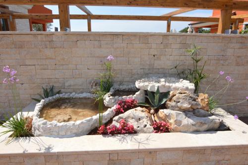 a rock garden with a fountain in front of a brick wall at Hotel Natura Vilanija in Umag