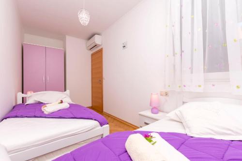 2 Betten in einem Zimmer mit Lila und Weiß in der Unterkunft Apartment Ivanka in Omiš