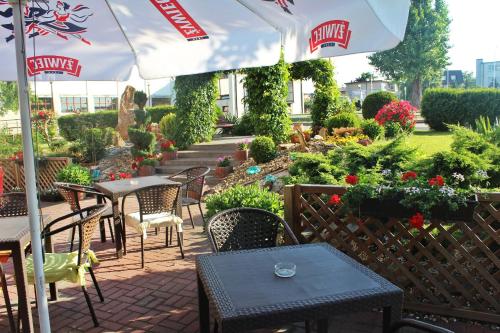 a patio with tables and chairs and an umbrella at Hotel Bursztyn in Kalisz