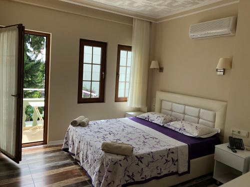 a bedroom with a bed with purple sheets and a window at Kalkan Dream Hotel in Kalkan