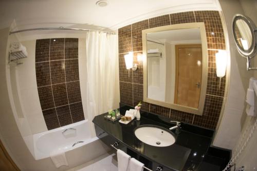 a bathroom with a sink and a mirror at Kuwait Grand Hotel in Kuwait