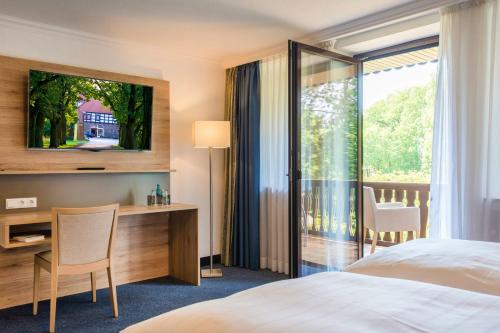 a hotel room with a bed and a desk and a window at IDINGSHOF Hotel & Restaurant in Bramsche