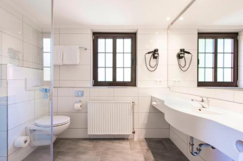 a white bathroom with a toilet and a sink at IDINGSHOF Hotel & Restaurant in Bramsche