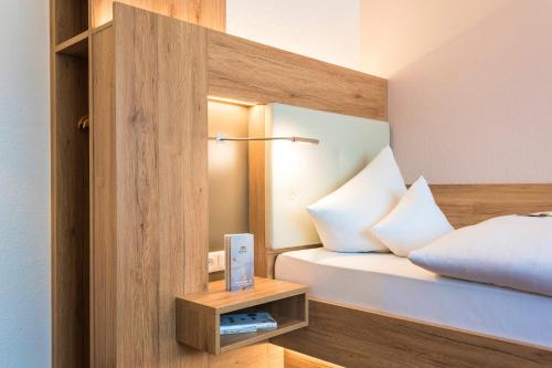 a bed with white pillows and a night stand next to it at IDINGSHOF Hotel & Restaurant in Bramsche