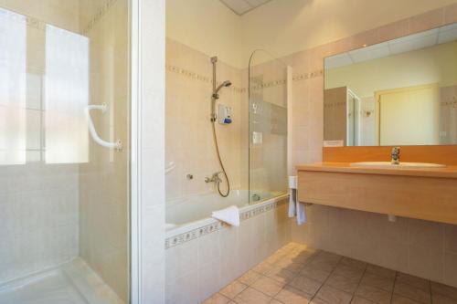 y baño con ducha y lavamanos. en Logis Hotel Restaurant Remotel, en Knutange