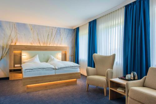 a hotel room with a bed and a chair at IDINGSHOF Hotel & Restaurant in Bramsche