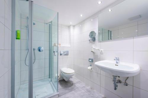 a bathroom with a shower and a sink and a toilet at IDINGSHOF Hotel & Restaurant in Bramsche