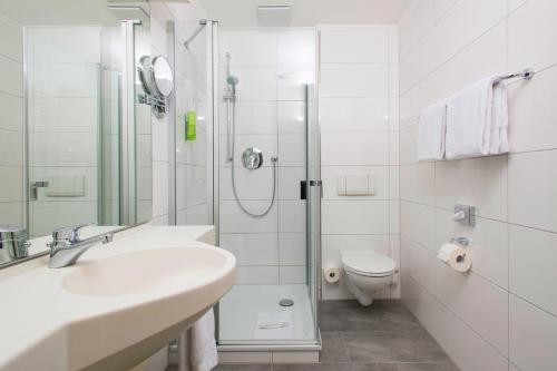 a bathroom with a shower and a sink and a toilet at IDINGSHOF Hotel & Restaurant in Bramsche