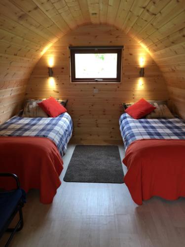 a room with two beds in a log cabin at Glendalough Glamping - Adults Only in Laragh