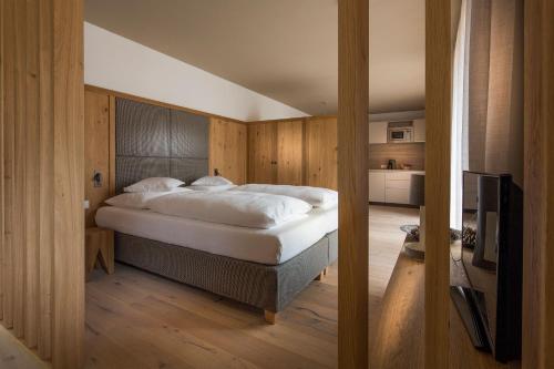 ein Schlafzimmer mit einem Bett und einem TV in einem Zimmer in der Unterkunft Mölgg Dolomites Residence in St. Vigil