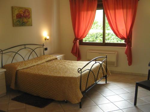 1 dormitorio con 1 cama y una ventana con cortinas rojas en B & B OASI, en Rosciano