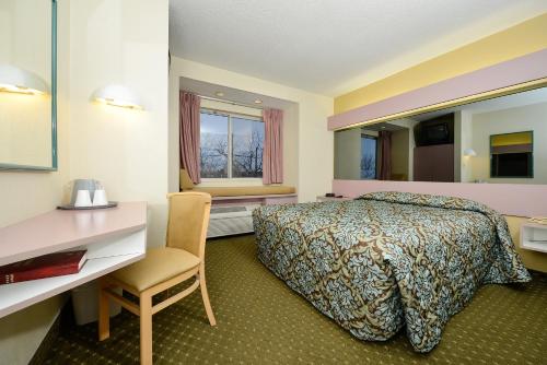 イースト・シラキ​​ュースにあるAmericas Best Value Inn - East Syracuseのベッドとデスクが備わるホテルルームです。