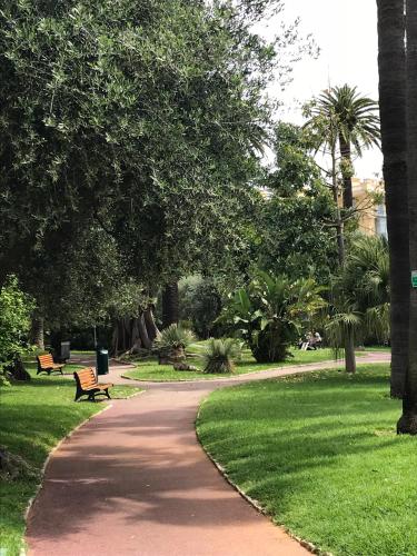 a path in a park with a bench and grass at Les Jasmins in Beaulieu-sur-Mer
