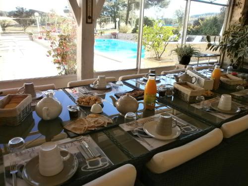 einen Tisch mit Speisen und Poolblick in der Unterkunft Chambres d'Hôtes Domaine de Beunes in Pailloles