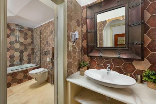 a bathroom with a sink and a toilet and a mirror at Villa Anastasia in Lindos