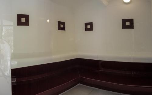 a bathroom with a white wall and brown benches at Hotel ADLER Carezza in Nova Levante