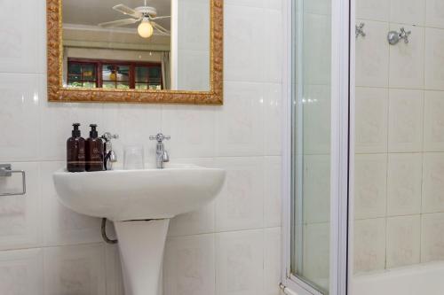 a bathroom with a sink and a shower and a mirror at Brighton Lodge - #Solar Energy #No Loadshedding in Port Elizabeth