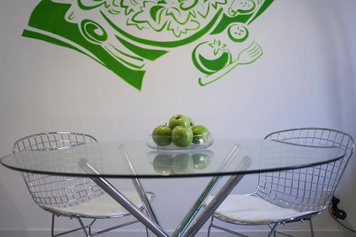 a glass table with two chairs and a bowl of apples at Habitat Apartments ADN in Barcelona