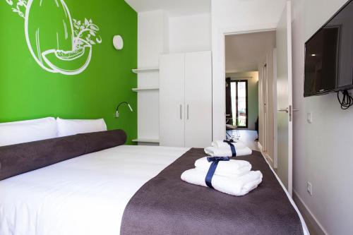 a bedroom with a white bed with a green wall at Habitat Apartments ADN in Barcelona