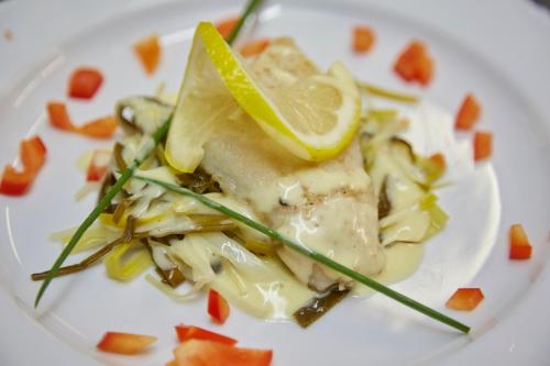a white plate with a piece of food with a lemon on it at Flair Hotel Villa Ilske in Bad Kösen