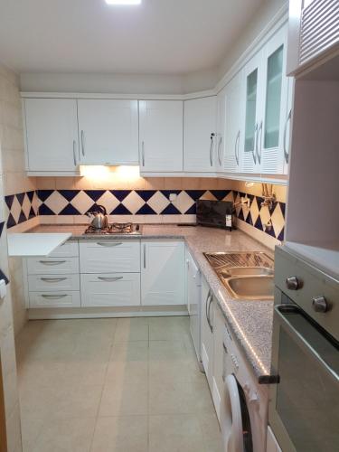 a white kitchen with white cabinets and a sink at Caia Formosa T1 in Cabanas de Tavira