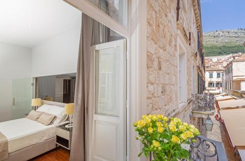 1 dormitorio con balcón con 1 cama y un jarrón de flores en Dubrovnik Palace W apartment, en Dubrovnik