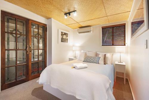 a bedroom with a white bed and a window at Gecko Shed in Byron Bay